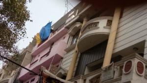 गुलाबी रंग की बिल्डिंग में नीले और पीले रंग के प्लास्टिक डालकर अवैध रूप से बनाई जा रही है पांचवी मंजिल